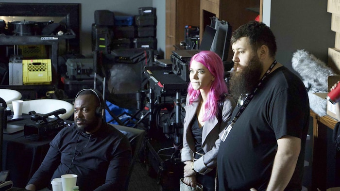 Trois personnes sont à l'intérieur d'un studio de production avec beaucoup d'équipement de son.