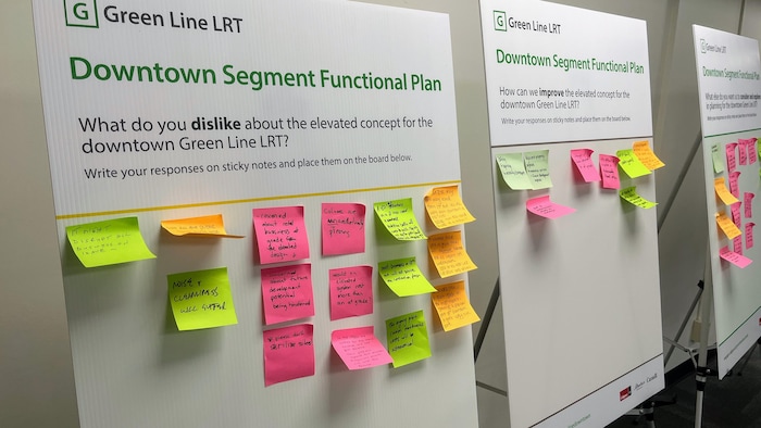 Trois grands panneaux d'information sur chevalets sont alignés dans une salle lors d'une consultation publique sur le projet de train léger Green Line LRT à Calgary. calgary-ligne-verte-trace-aerien-consultation-commerce