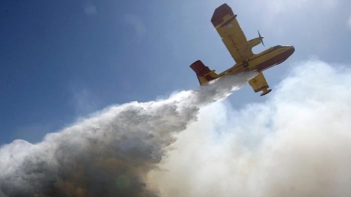 Un avion-citerne largue de l’eau sur un feu de forêt.