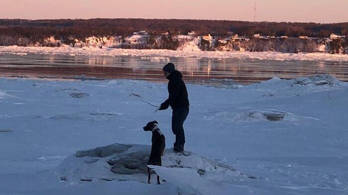 Un homme joue avec son chien dans la neige.
