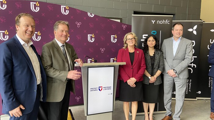 5 représentants prennent leur photo à coté du podium.