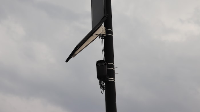 Une caméra et un panneau solaire attachés à un lampadaire.