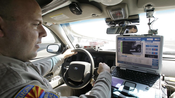 David Callister, agent du Département de la sécurité publique de l’Arizona, surveille l’ordinateur de bord de sa voiture de patrouille alors que celui-ci lit les plaques d’immatriculation des véhicules croisés grâce à une caméra infrarouge montée sur le pare-chocs avant, le mardi 14 août 2007 à Phoenix.