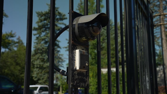 Une caméra de sécurité sur une clôture métallique.