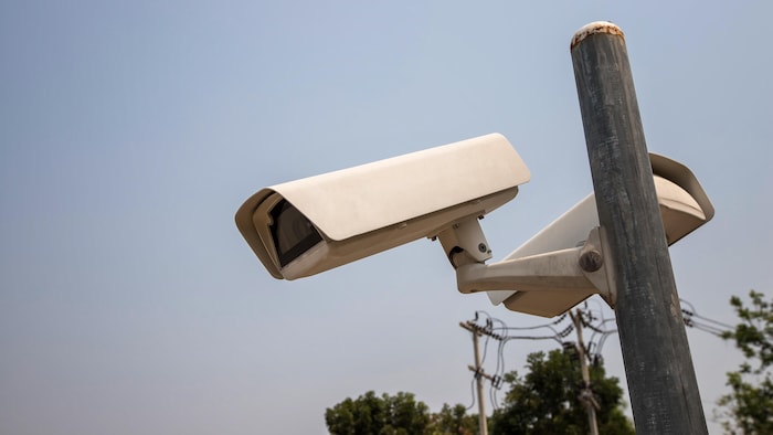 Des caméras de surveillance montées sur un poteau, à l'extérieur. 