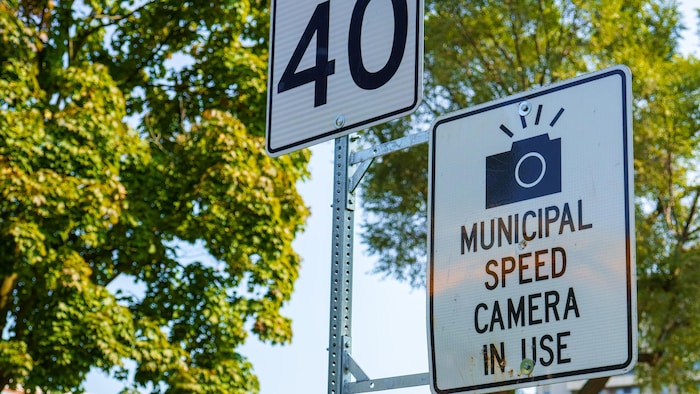Près d'une école, deux panneaux de signalisation. L'un indique que la limite de vitesse est de 40 kilomètres à l'heure et l'autre prévient de la présence d'une caméra installée par la municipalité.