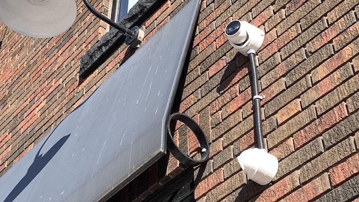 Deux caméras de surveillance sont installées sur un mur extérieur de brique.