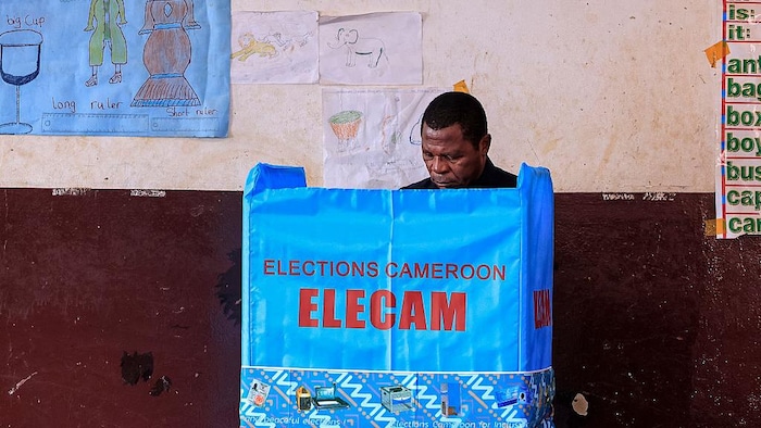 Atanga Nji est en train de voter dans un isoloir.