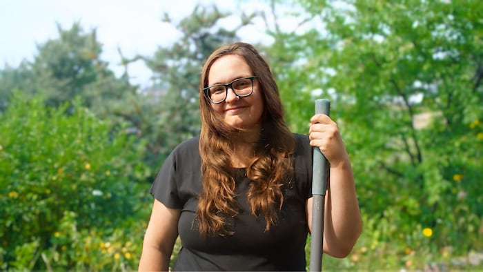 Camille Tremblay Beaulieu tenant un râteau posant devant des arbres.