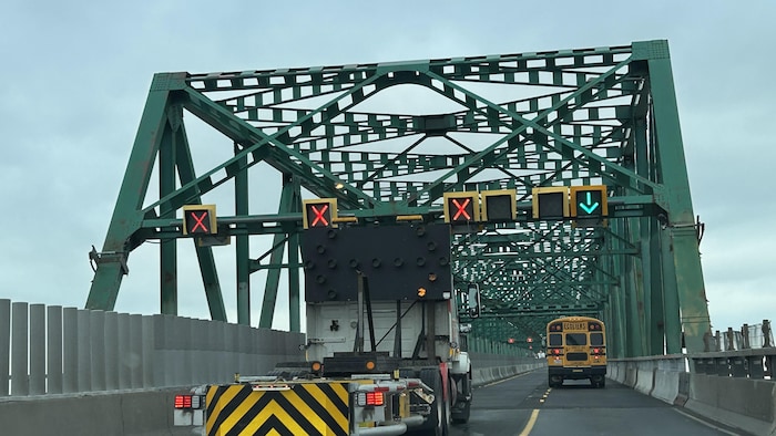 Un autobus scolaire passe à côté d'un camion qui bloque une voie.