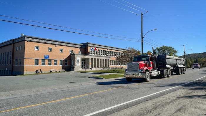 Un camion passe sur une route devant une école.