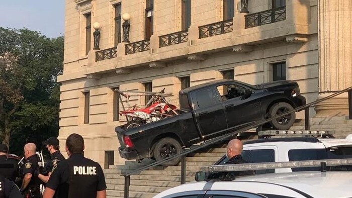 Un camion sur les marches du palais législatif avec des policiers aux alentours.