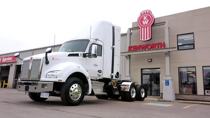 Un camion de transport de marchandises blanc devant le concessionnaire.