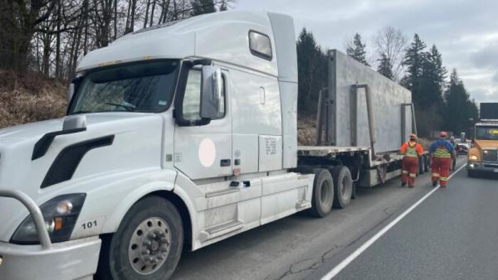 Un camion poids lourd avec un morceau de béton fabriqué sur une remorque est arrêté sur le bord de l'autoroute.