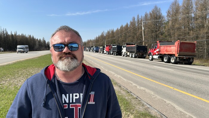 Raynald Pilote devant un convoi de camions.