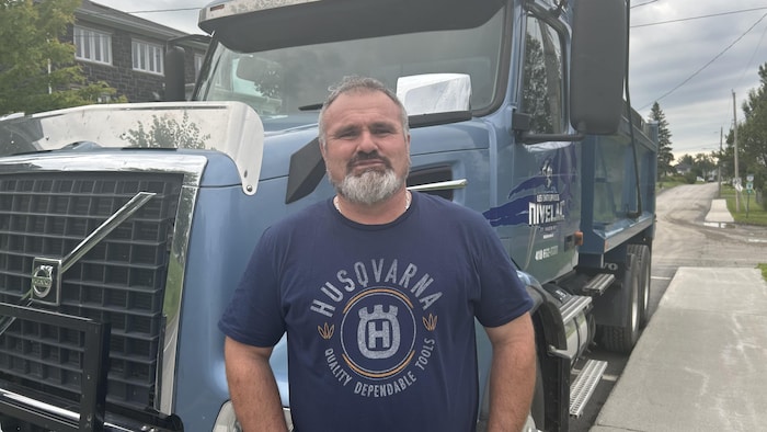 Un homme pose devant son camion.