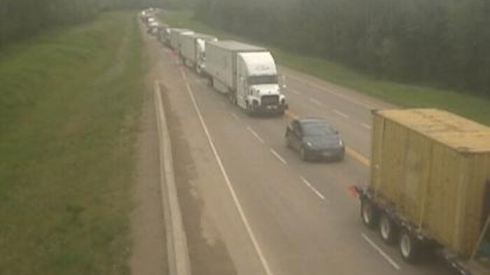 Une file camions et de voiture sur une route. 