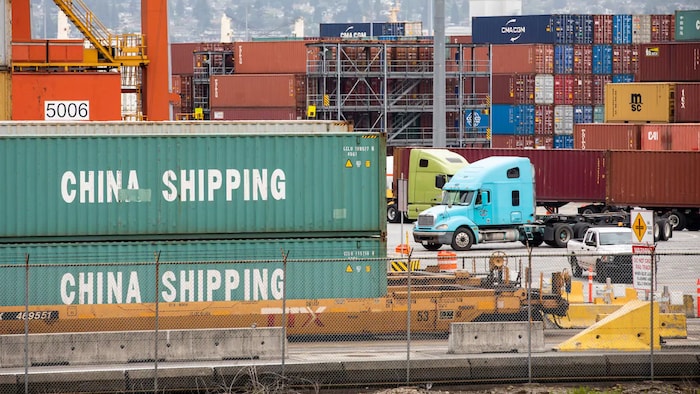Des conteneurs empilés et des camions garés dans le port de Vancouver.