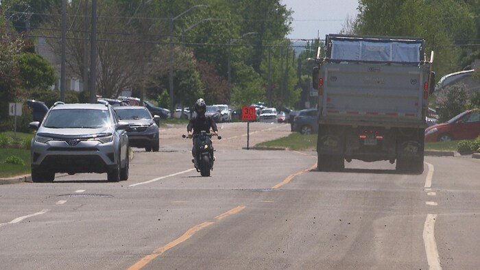 Un camion et un motocycliste sur une rue.