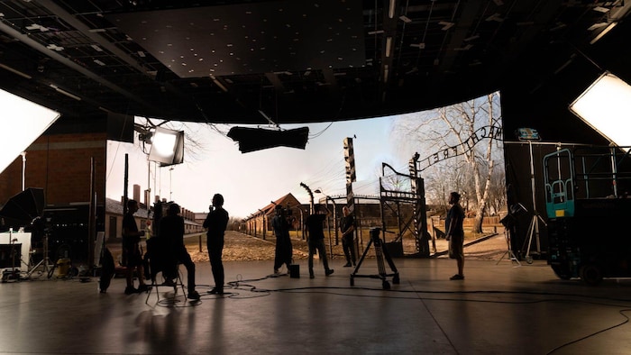 Des gens tournent du visuel devant une réplique numérique du campy de attraction d'Auschwitz.