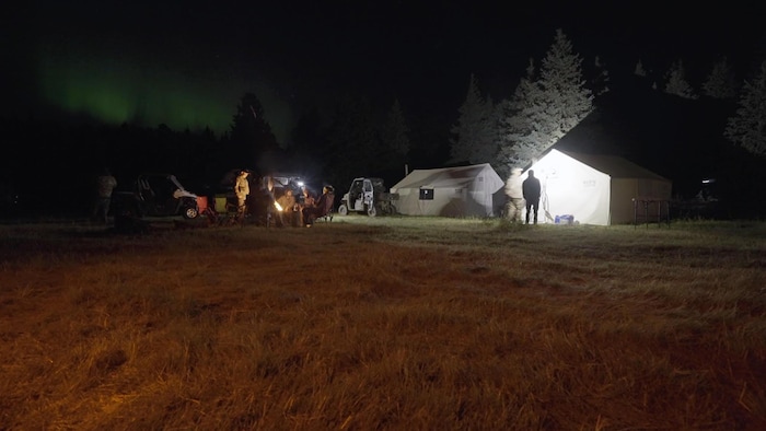 Une photo prise la nuit montrant des tentes et un feu de camp.
