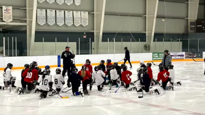Bradley Gibbs donnant un camp de hockey à des jeunes sur un patinoire. 