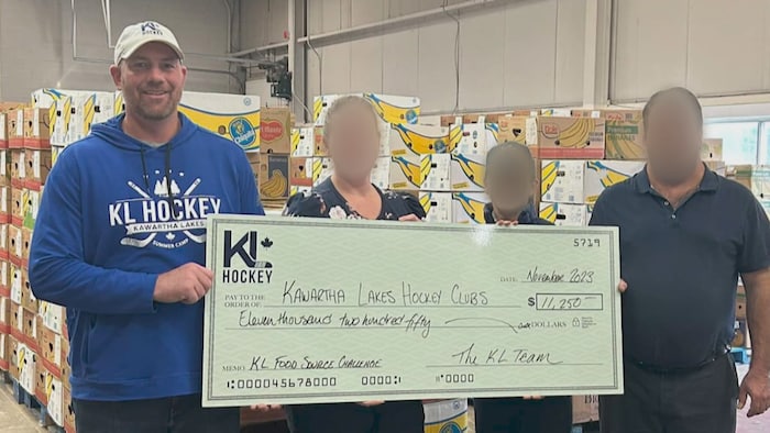 Bradley Gibbs remet un chèque géant à une banque alimentaire.