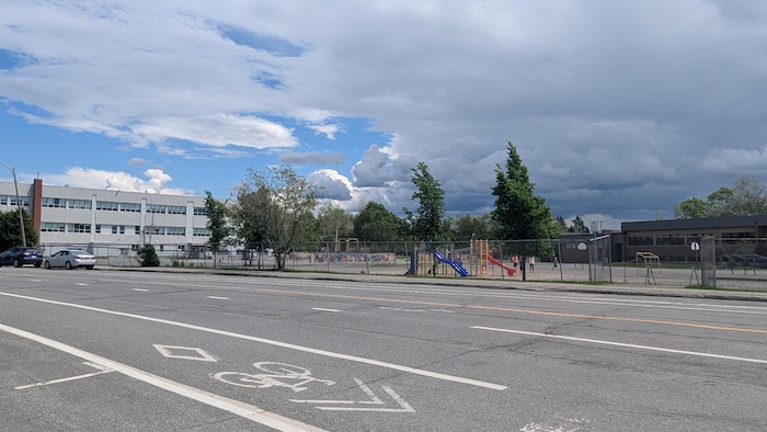 De l'autre côté de la rue, on voit l'école et sa cour de récréation.