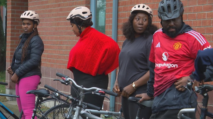 Des participants, casque sur la tête, se préparent à enfourcher leur vélo.