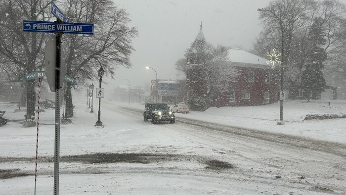 Une voiture conduit sur une rue légèrement enneigée du centre-ville de Campbellton. 