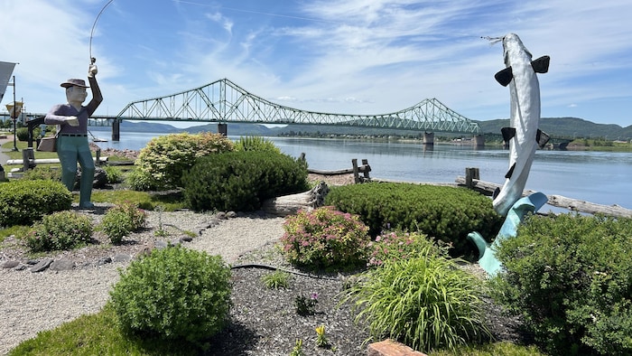 Le pont JC Van Horne, des statues et un sentier près de l'eau en avant plan.