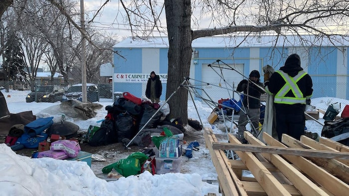 Des personnes qui démantèlent un campement de sans-abri.