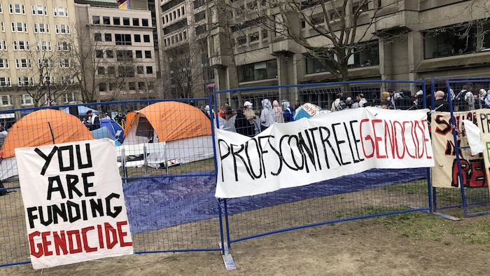 Un campement est entouré de banderoles qui portent les mentions « You are funding genocide » et « Profs contre le génocide ».