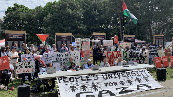 Une conférence de presse des organisateurs du campement propalestinien, assis à une table.