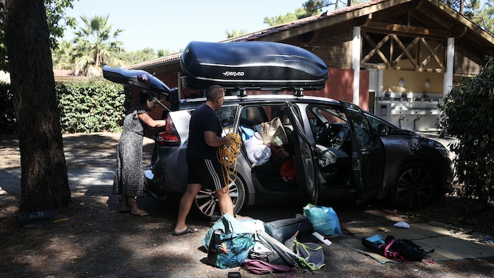 Un homme et une femme remplissent une voiture de matériel de camping.