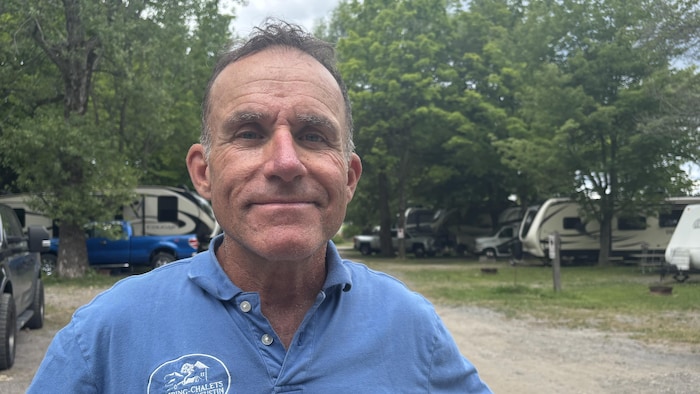Martin Grégoire sourit à la caméra dans un chemin de gravier de son camping.