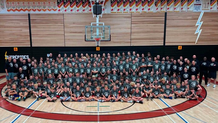 Plusieurs joueurs de basketball posent pour une photo dans un gymnase.