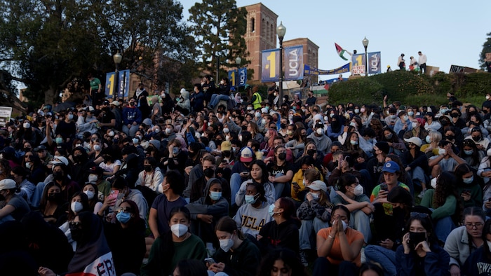 Des manifestants propalestiniens s'assoient sur l'herbe près d'un campement sur le campus de l'Université de Californie à Los Angeles (UCLA) le 2 mai 2024 à Los Angeles, en Californie. 