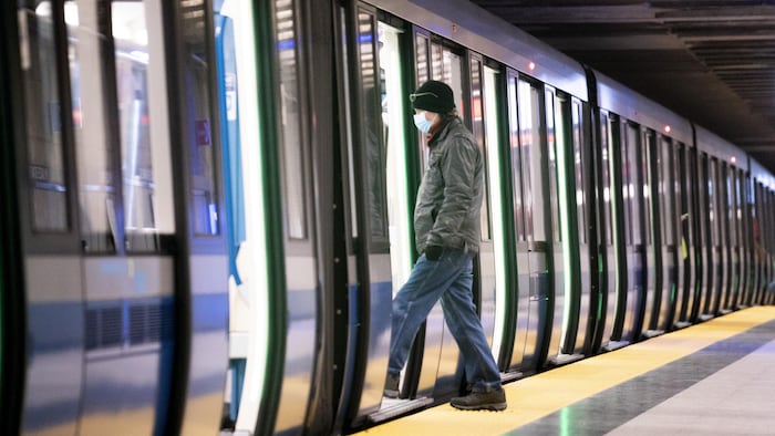Un homme masqué entre dans un métro.