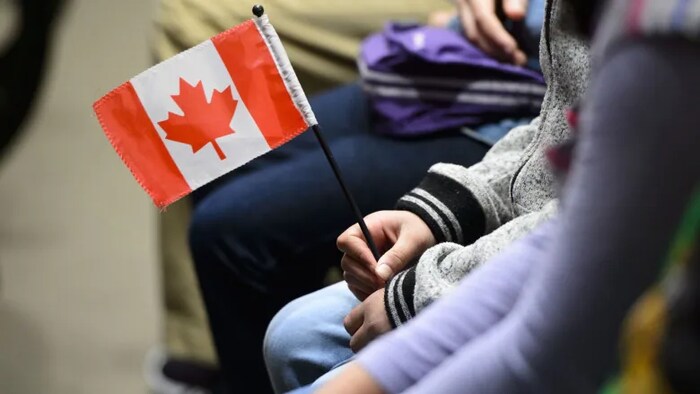 A young new Canadian holds a flag as she takes part in a citizenship ceremony on Parliament Hill in Ottawa on April 17, 2019. 