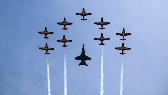 Les Snowbirds et un CF-18 survolent le ciel.