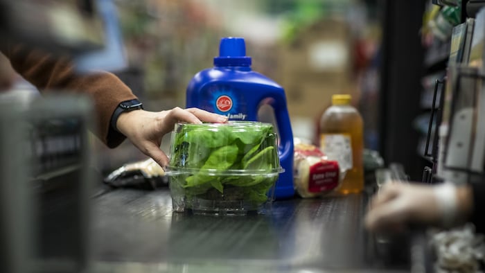 Une personne enregistre des produits à une caisse dans une épicerie.