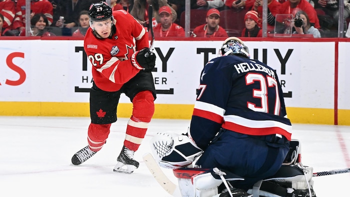 Le gardien des États-Unis Connor Hellebuyck bloque un tir de Nathan MacKinnon.