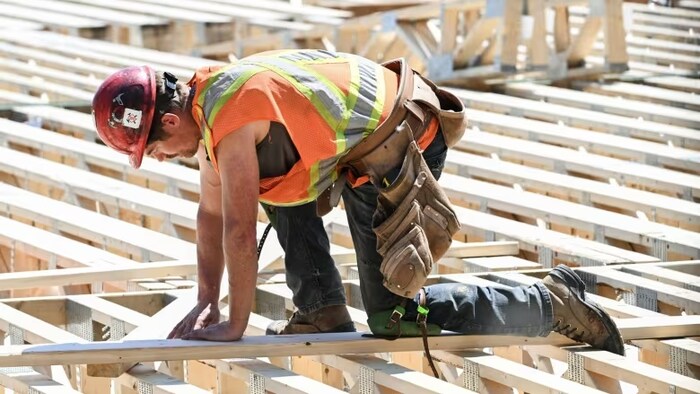 Un ouvrier mesure du bois sur un chantier de construction résidentielle à Montréal.  Selon la SCHL, le Canada doit construire 3,5 millions de logements supplémentaires au-delà de ce qui est actuellement prévu pour fournir une offre de logements adéquate d'ici 2030. (Graham Hughes/Bloomberg)