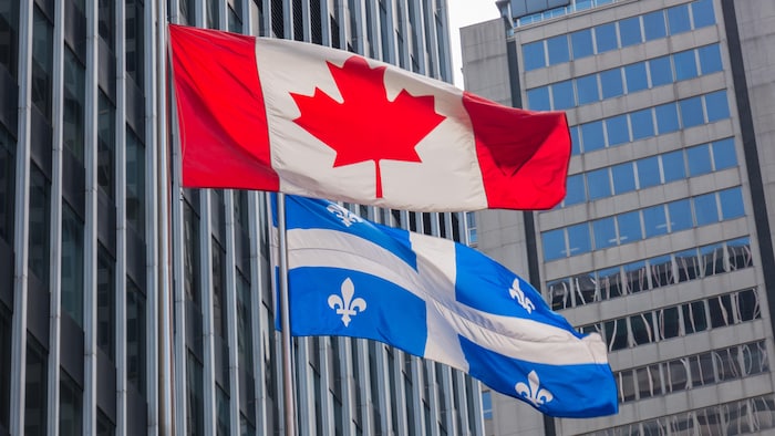 Des drapeaux canadien et québécois au vent.