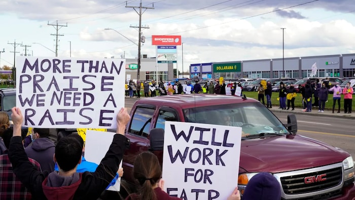 Canadian Union of Public Employees supporters hold up signs along Champlain Street during a strike, in Moncton in November 2021. But economists suggest that wage increases are not driving inflation. (John Morris/Reuters)