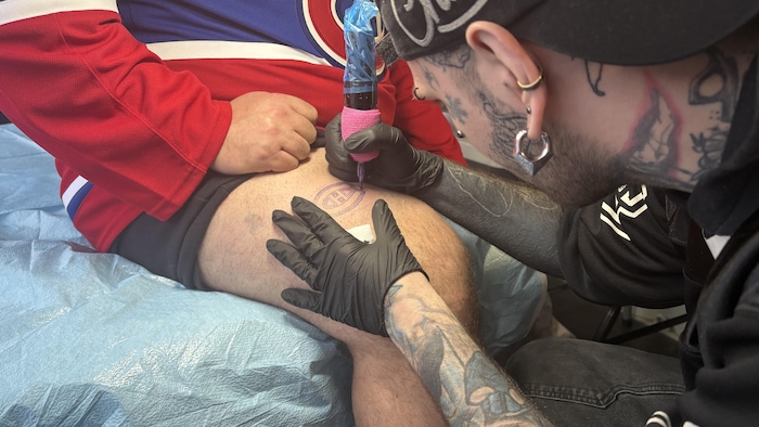 Un partisan du Canadien se fait tatouer le logo de l'équipe sur la cuisse.