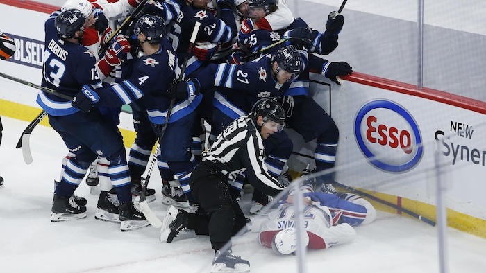Une mêlée sur la glace. Des joueurs se chamaillent. Un juge de ligne protège un joueur inconscient.