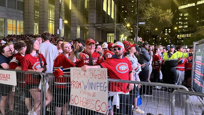 Des partisans venus de Winnipeg brandissent une pancarte devant un écran géant à l'extérieur du Centre Bell, le 27 mai 2026.