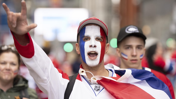 Un supporter dont le visage est peint en bleu, blanc et rouge.